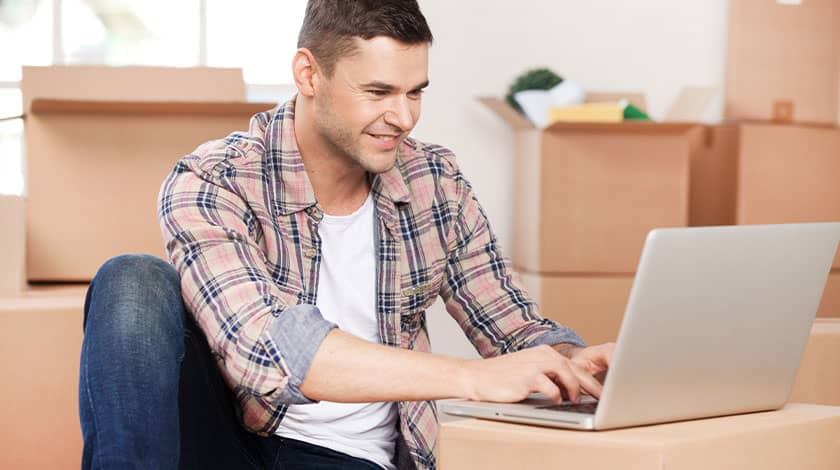 Man Using Laptop with Boxes all Around