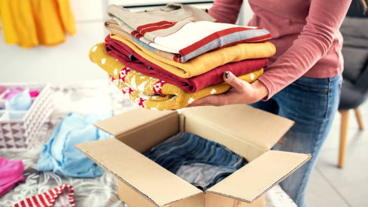 Woman placing folded clothes into boxes