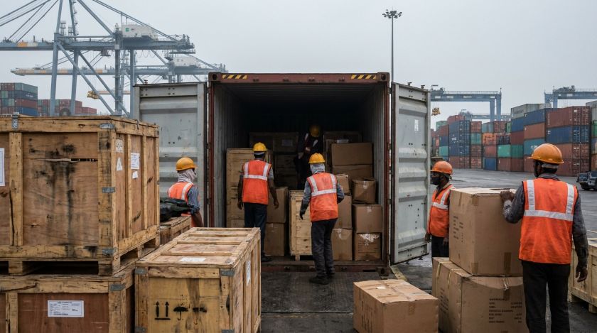 Wooden crates and cardboard boxes being loaded into a shipping container at a port for an international household move