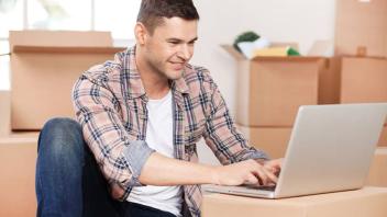 Man Using Laptop with Boxes all Around